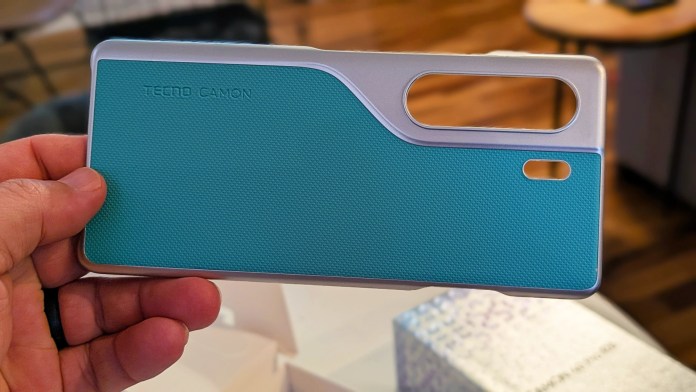 An individual holding a TECNO Camon phone case featuring a textured turquoise design and a silver border, highlighting its unique design elements.