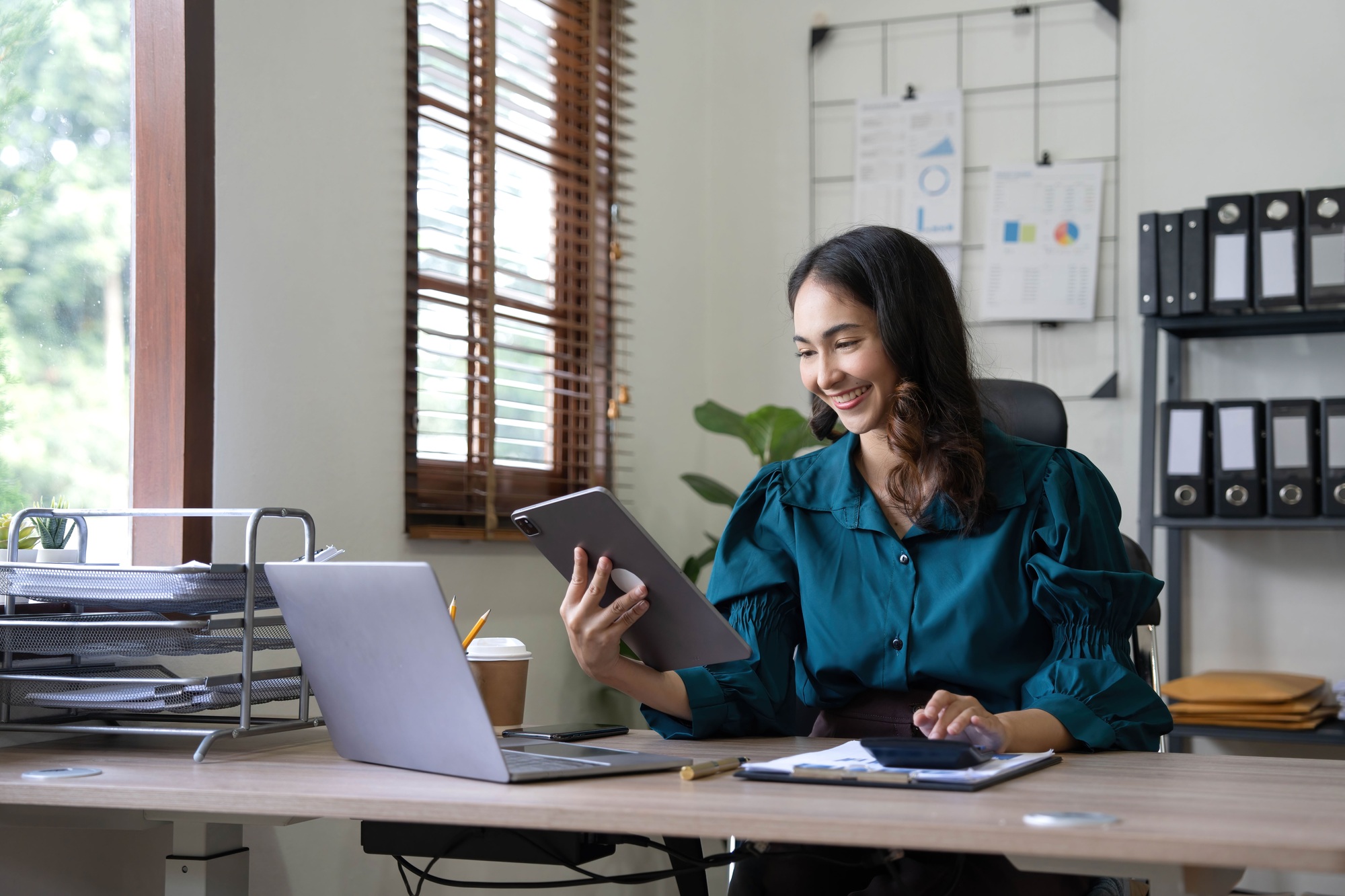 Asian indian Female director working in the office sitting at a desk analyzing business statistics