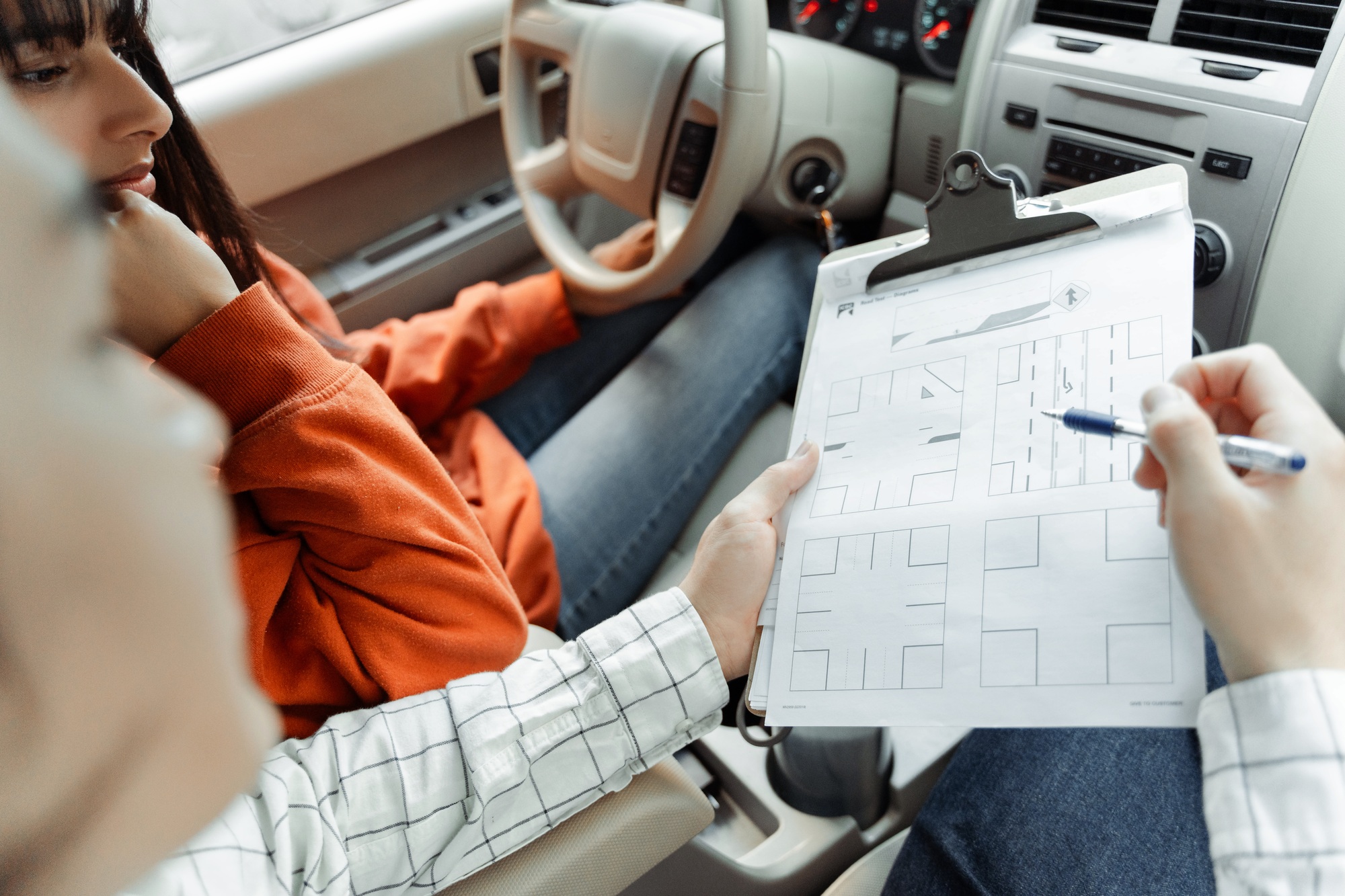 Driving instructor explaining parking maneuver to student during exam