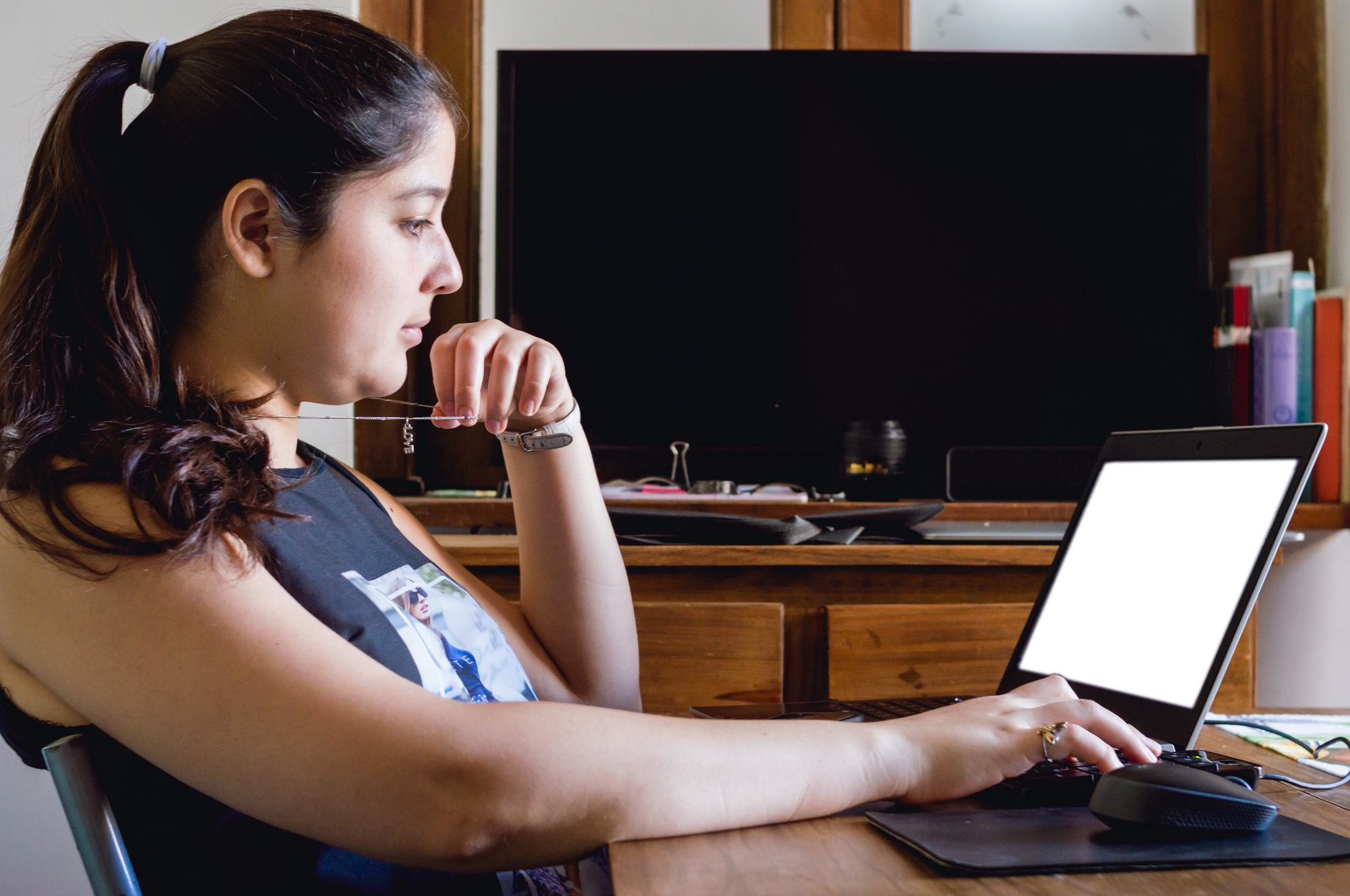young woman sitting at home working analyzing data and statistics on her computer