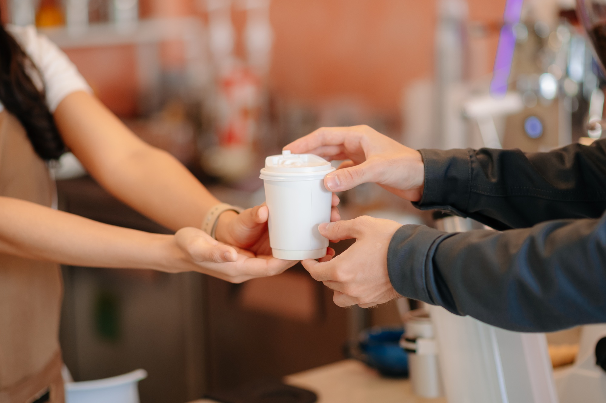 Barista facilitating a contactless payment using a card reader and smartphone. Capturing modern