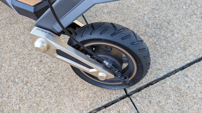 Close-up of the rear wheel and suspension system of the Navee ST3 Pro scooter, showcasing the intricate design of the dampening arm and tire tread.