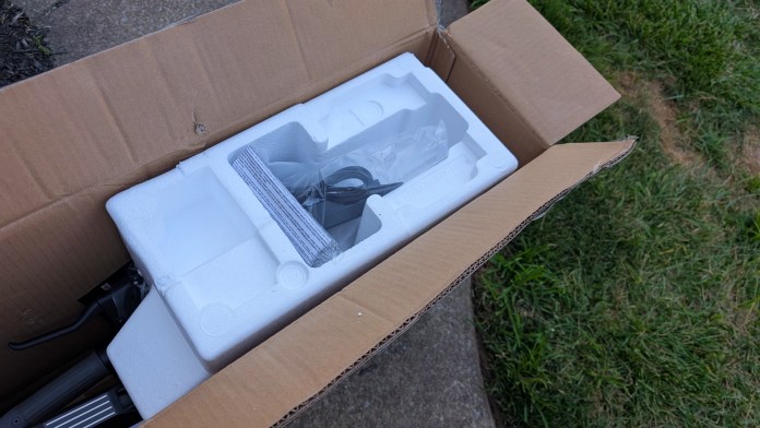 An open cardboard box revealing protective foam packaging and components for the Navee ST3 Pro scooter.
