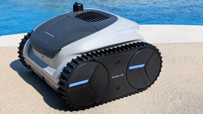 A robotic pool cleaner with a sleek design, featuring tracks for grip, positioned next to a pool with blue water.