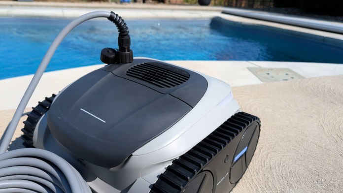 Close-up of the Bublue BuHybrid L6 robotic pool cleaner, featuring a hose connection and part of a swimming pool in the background.