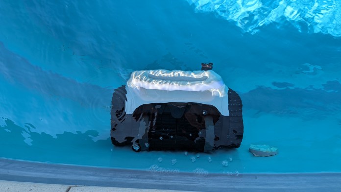 A robotic pool cleaner submerged in a blue swimming pool, showcasing its sleek design and operational features.