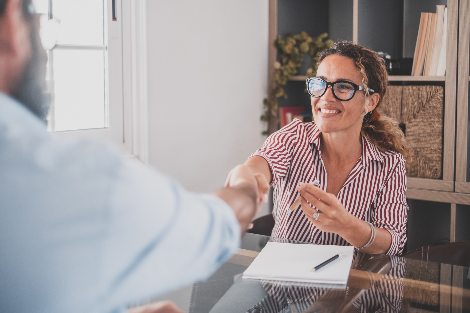 Smiling caucasian female hr manager handshake hire male candidate at job interview
