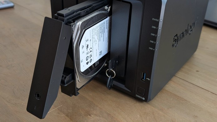 Close-up view of the Synology DS925+ NAS with a hard drive partially inserted and locked, showing the front panel with drive status indicators.