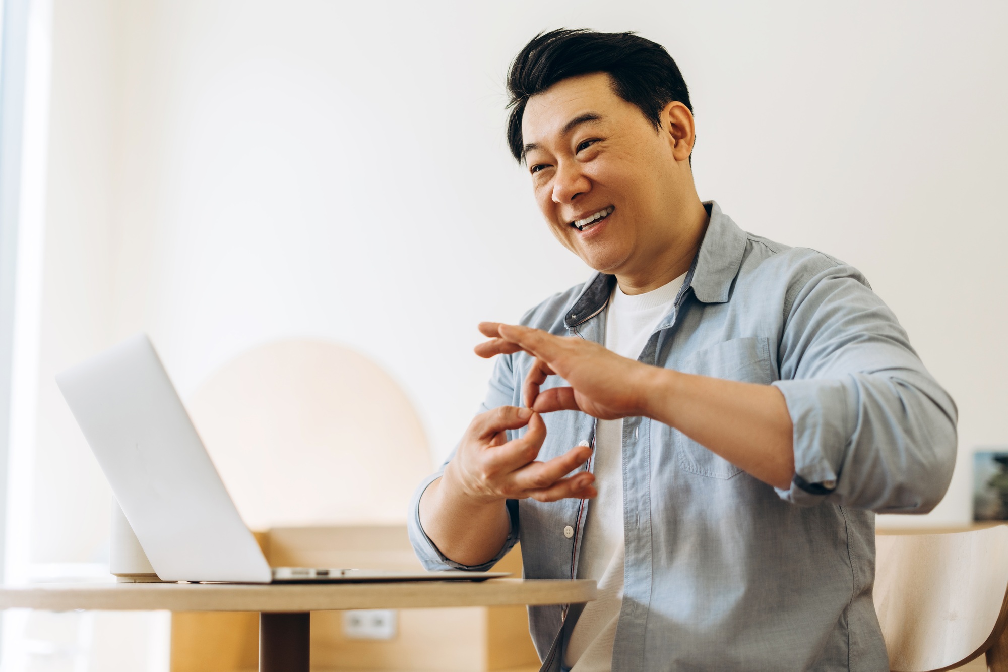 Asian man using sign language during video conference on laptop