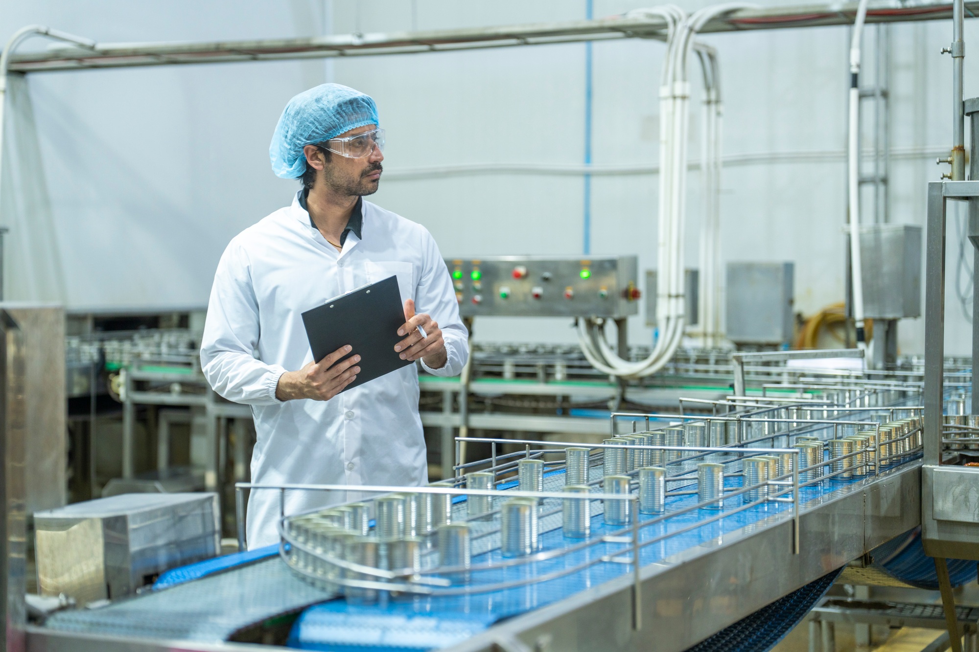 Factory technician in a clean uniform conducting a detailed inspection
