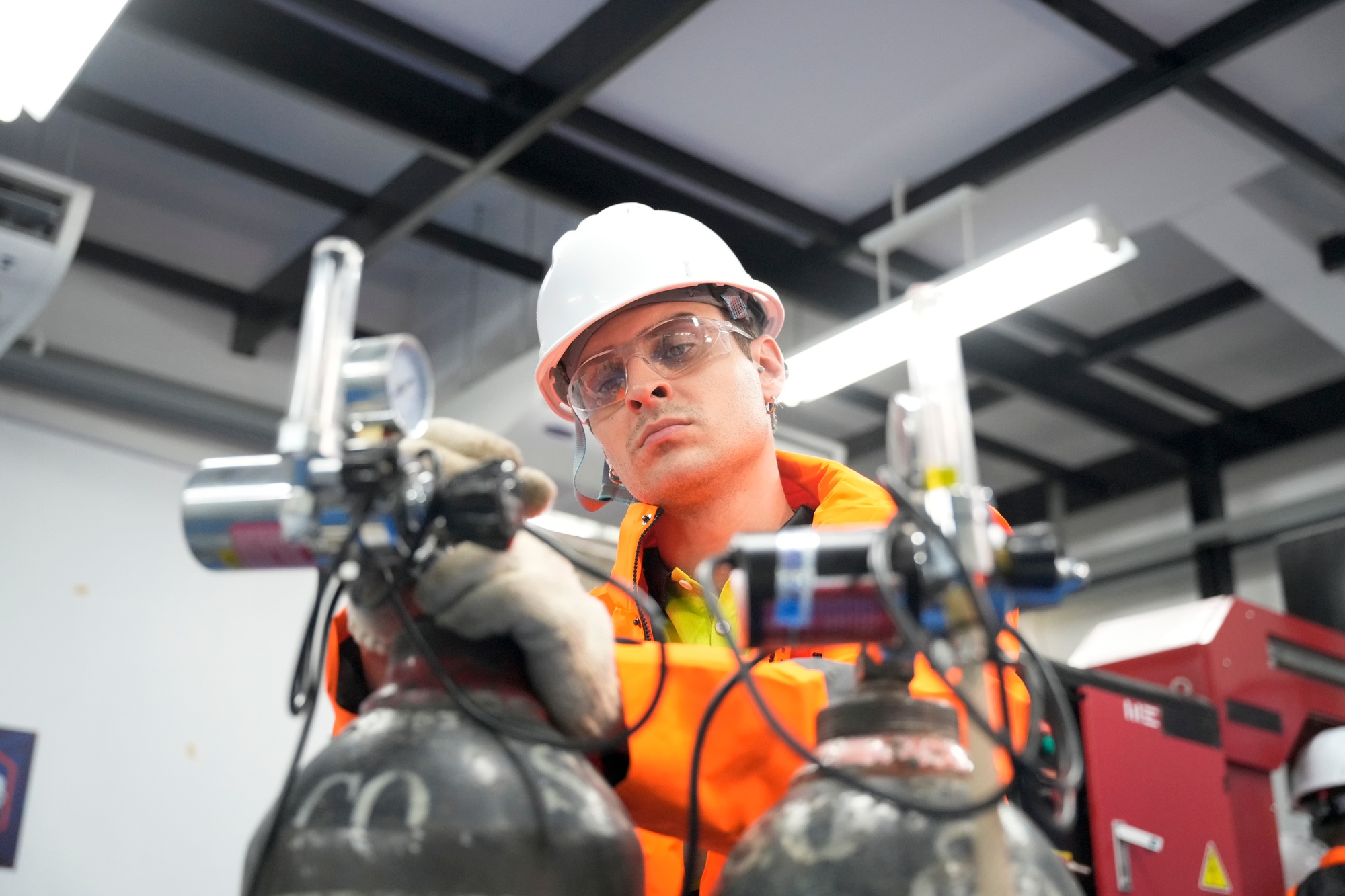 Technician prepares gas cylinders in a safety-focused engineering environment