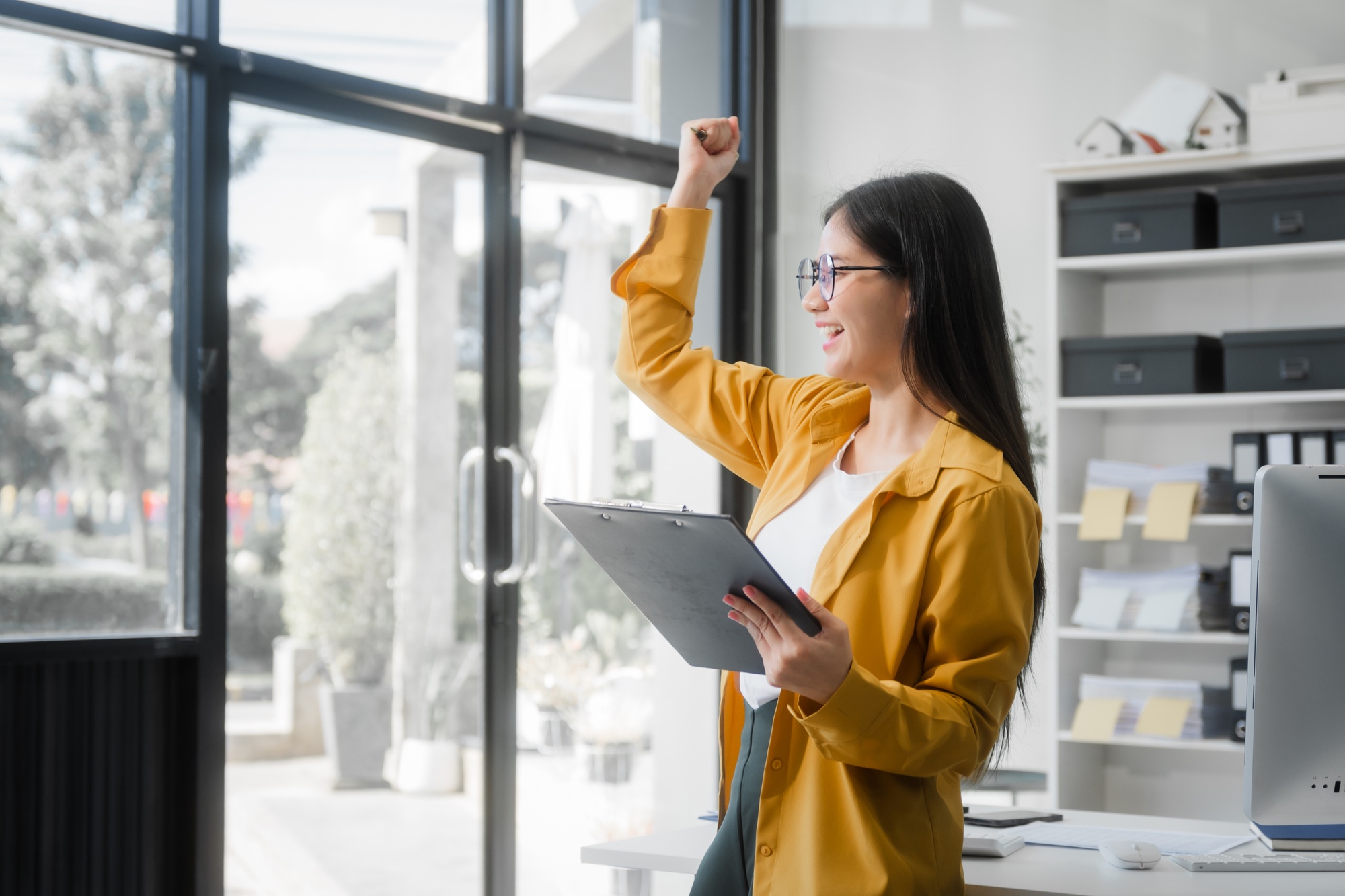 Young Asian woman at desk, managing HR, legal consulting, and compliance amidst files