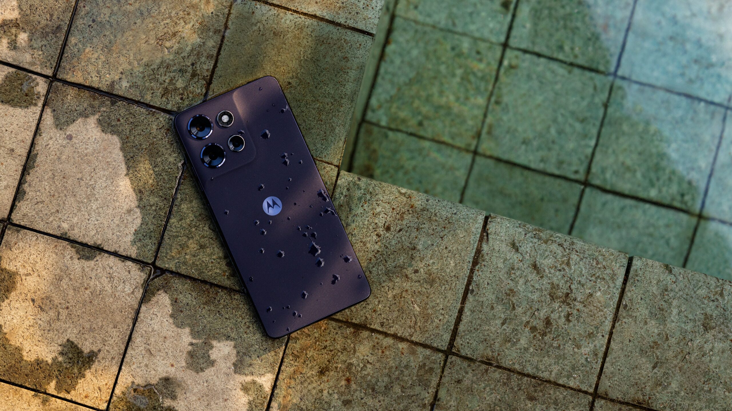 Moto G Power 2026 in Pantone evening blue with water splashes lying face down on the ground