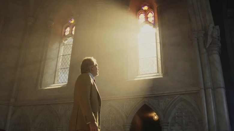 Benoit Blanc, bathed in sunlight streaming in through a church window, in Wake Up Dead Man